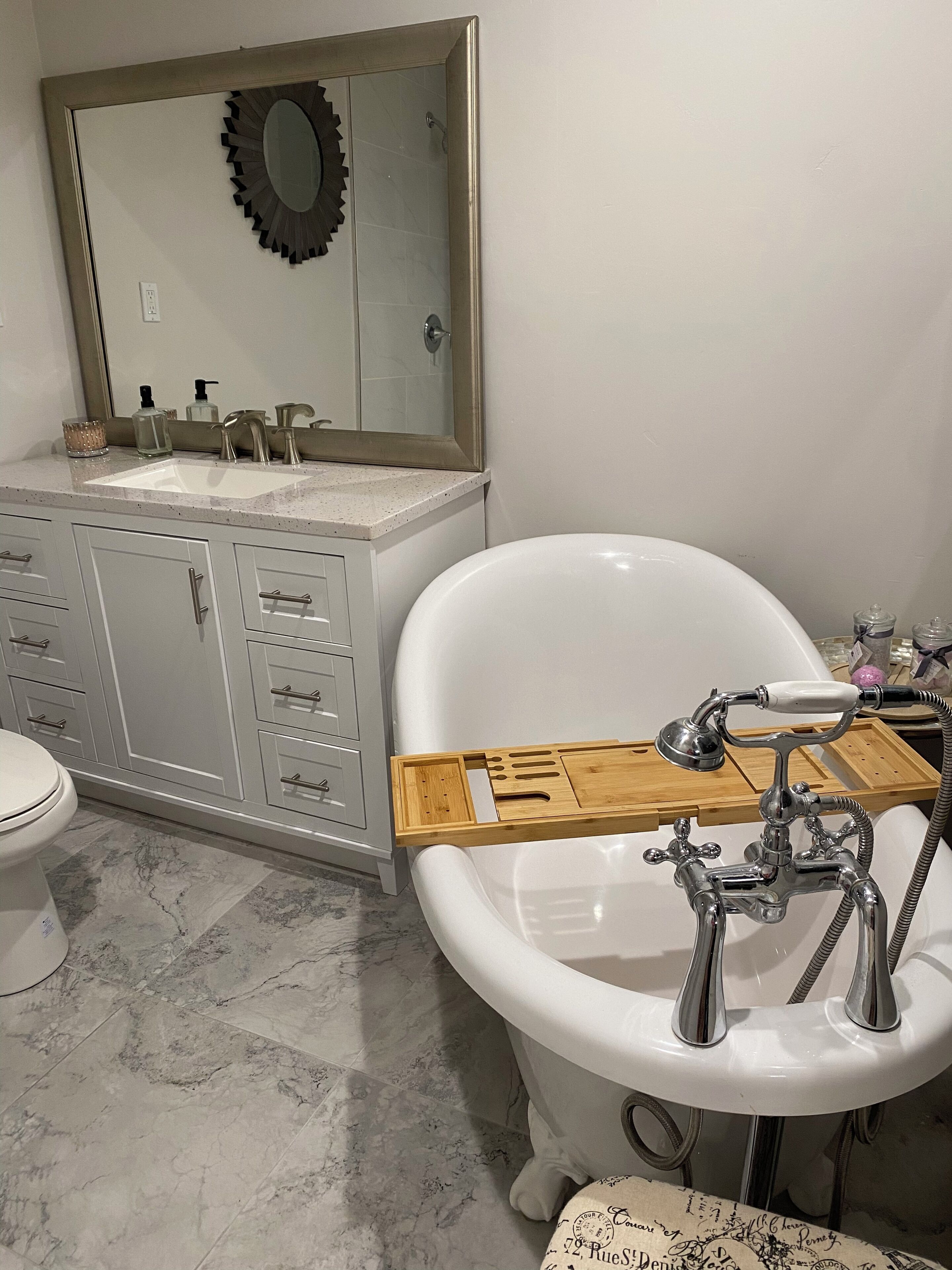Ein Badezimmer mit freistehender Badewanne, einem Waschtisch mit Spiegel und einer Toilette.