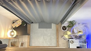 Et moderne hotelværelse med en stor seng, et lille skrivebord, en potteplante og en loftsvifte.