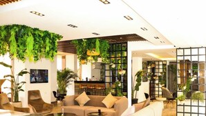 En moderne lobby med en sofa, stole, et marmorbord og grønne planter.