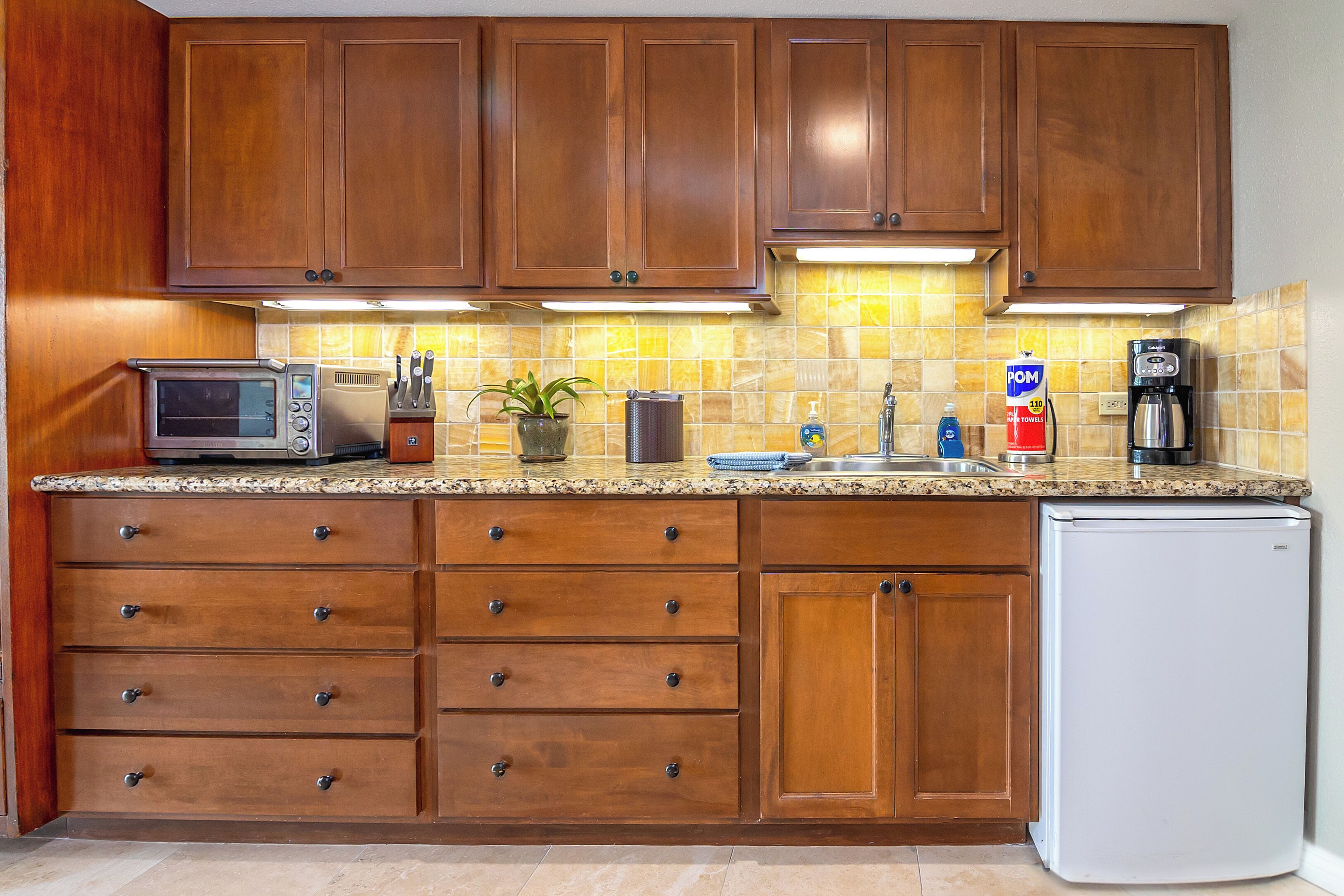 A kitchen with wooden cabinets, a microwave, a coffee maker, and a refrigerator.