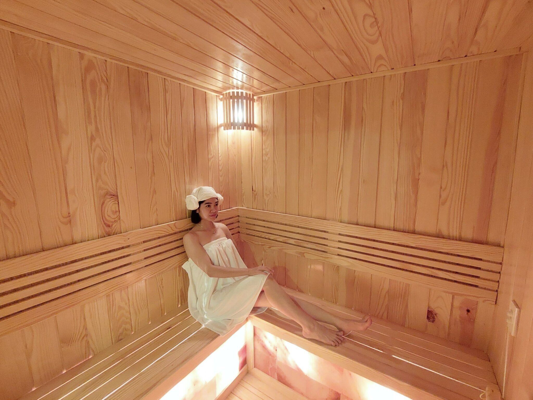 Una sauna de madera con bancos y una lámpara en el centro.