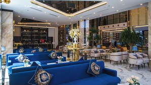 Un hall d’hôtel moderne avec des canapés bleus, un bar et un espace salon équipé de tables et de chaises.