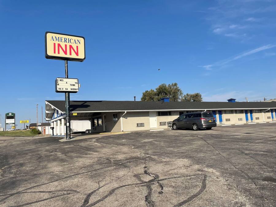 An American Inn with a signboard, a parking lot, and a building with a flat roof.