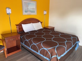 Una habitación de hotel con una colcha marrón estampada, mesitas de noche de madera y un cuadro enmarcado en la pared.