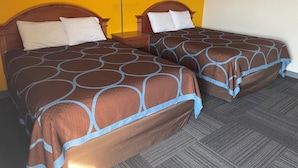 Two double beds with brown and blue patterned bedspreads, a nightstand, and a wall-mounted lamp. - American Inn Motel (Pratt)