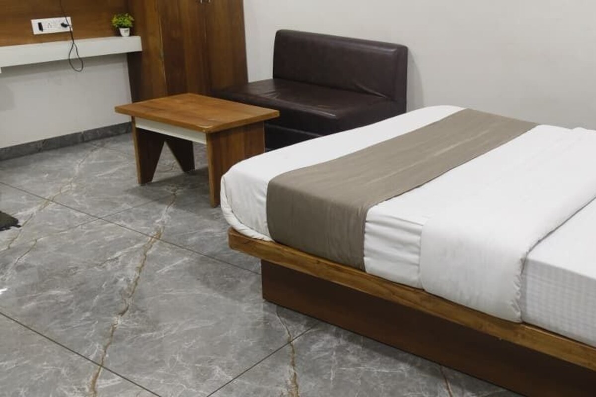 A bedroom with a bed, a wooden nightstand, a small table, and a dark leather chair.