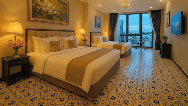 Quarto de hotel com duas camas, um candelabro, uma janela grande com vista para a cidade e ladrilhos no chão com padrão.