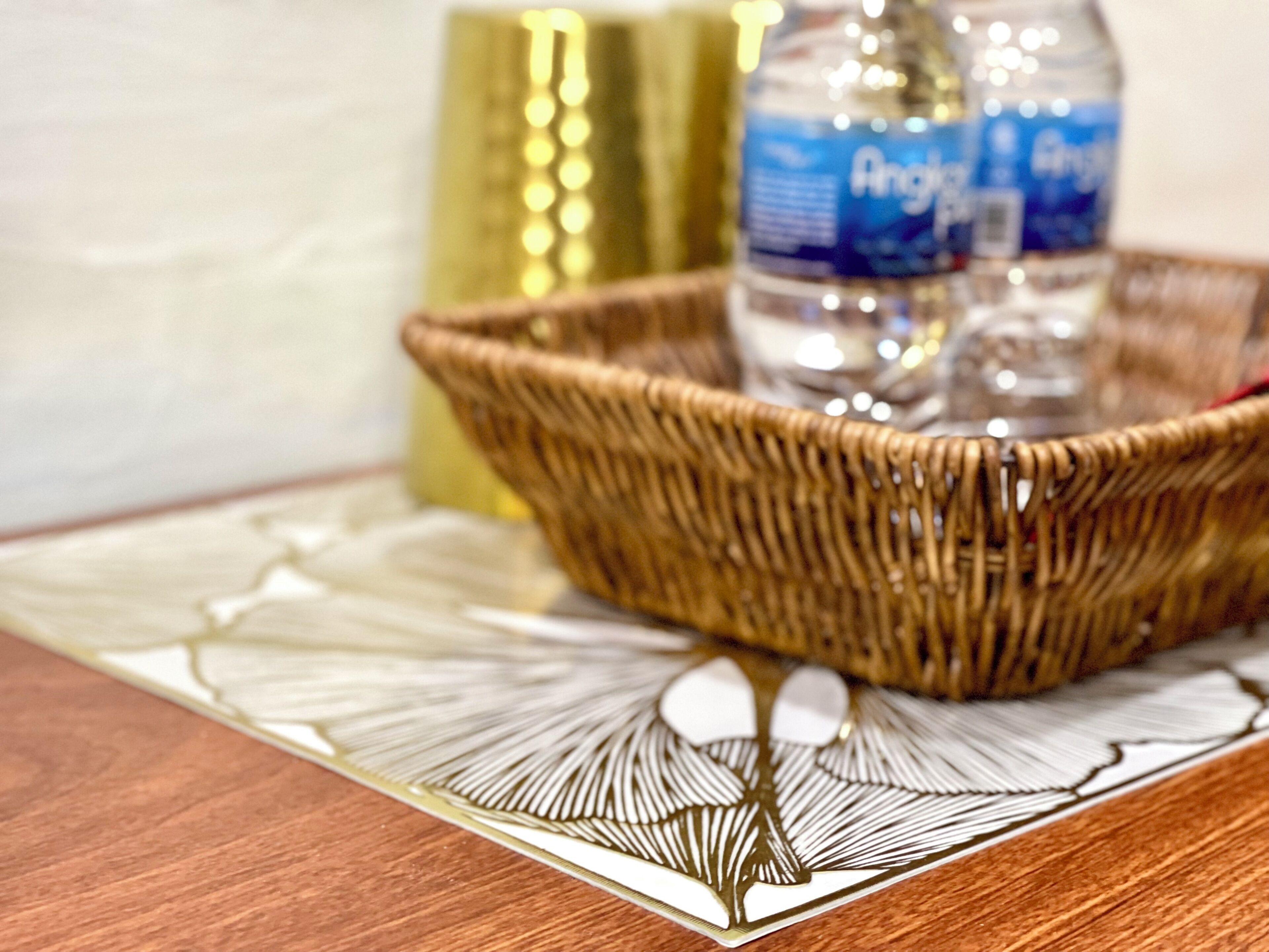 A wicker basket on a table with a bottle and a decorative item.