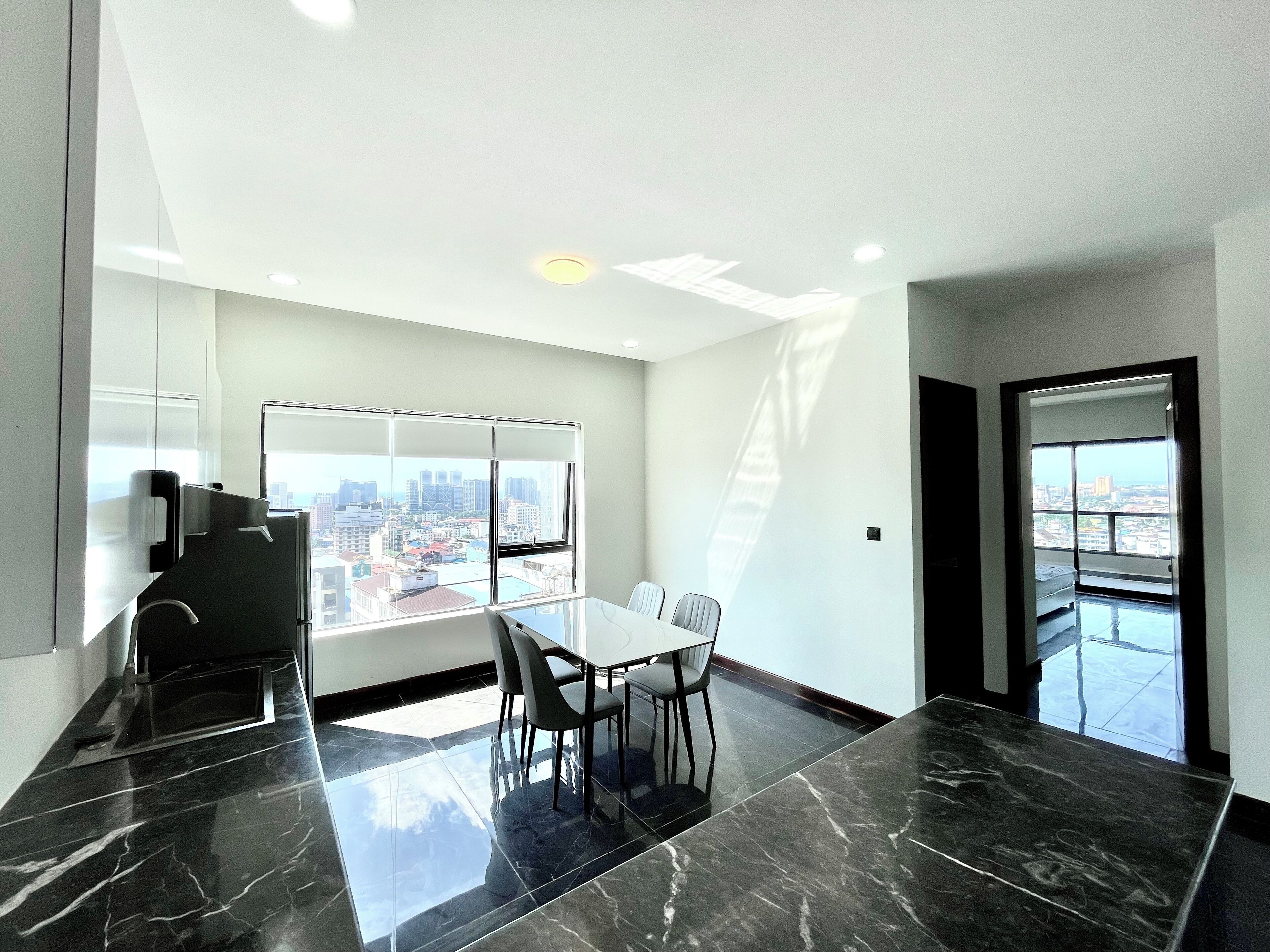 A modern conference room with a glass table, chairs, a whiteboard, and a city view through large windows.