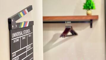 Un clapperboard con la leyenda 'UNIVERSAL STUDIOS' y la palabra 'ROLL' visible, una estantería con una planta y un estante de madera con un adorno.