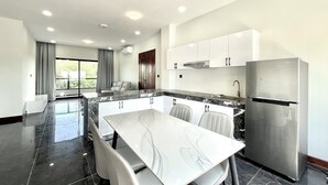 A modern kitchen with a marble countertop, stainless steel appliances, and a dining area with a white table and chairs.