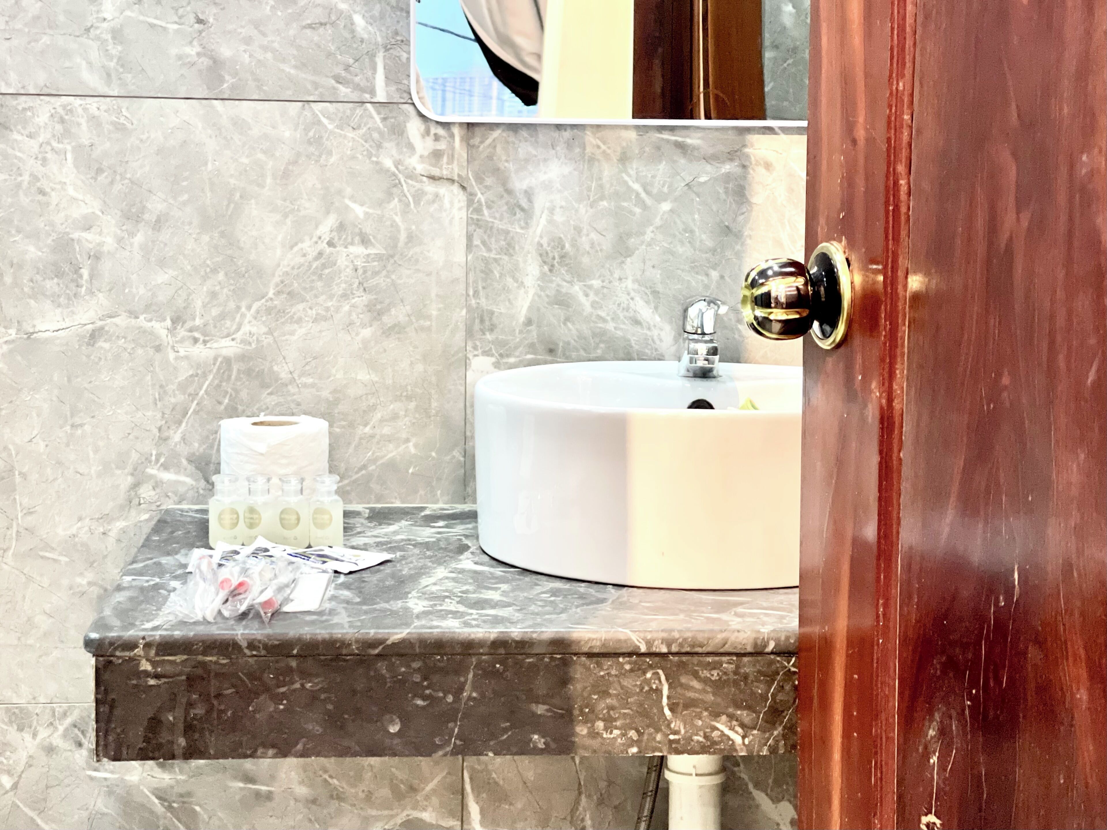 Une salle de bain avec un lavabo en marbre, un miroir et des articles de toilette posés sur le comptoir.