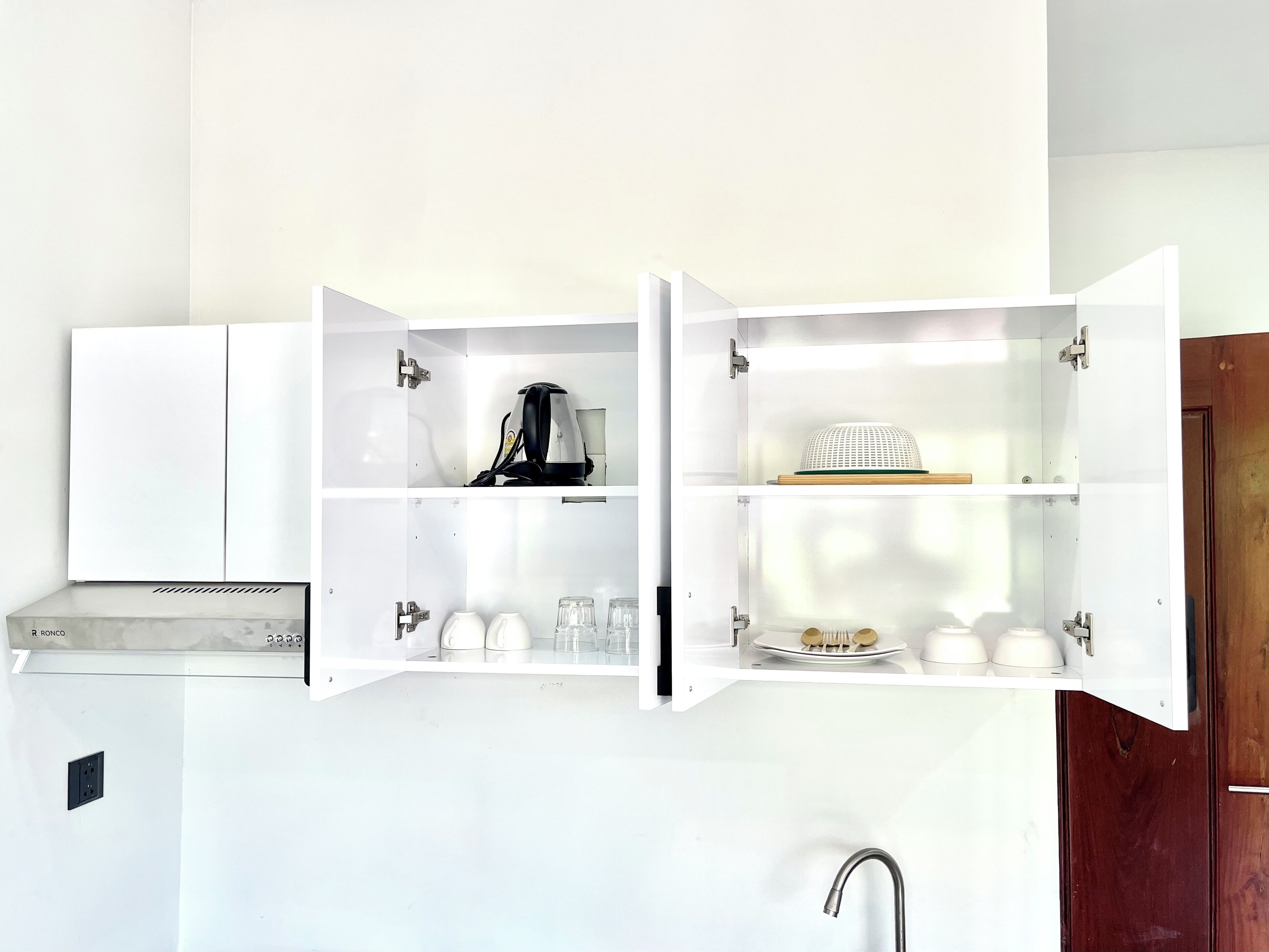 A kitchen with white cabinets, a coffee maker, and a sink.