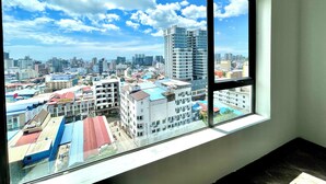 A view from a window overlooking a cityscape with various buildings, including a prominent high-rise.