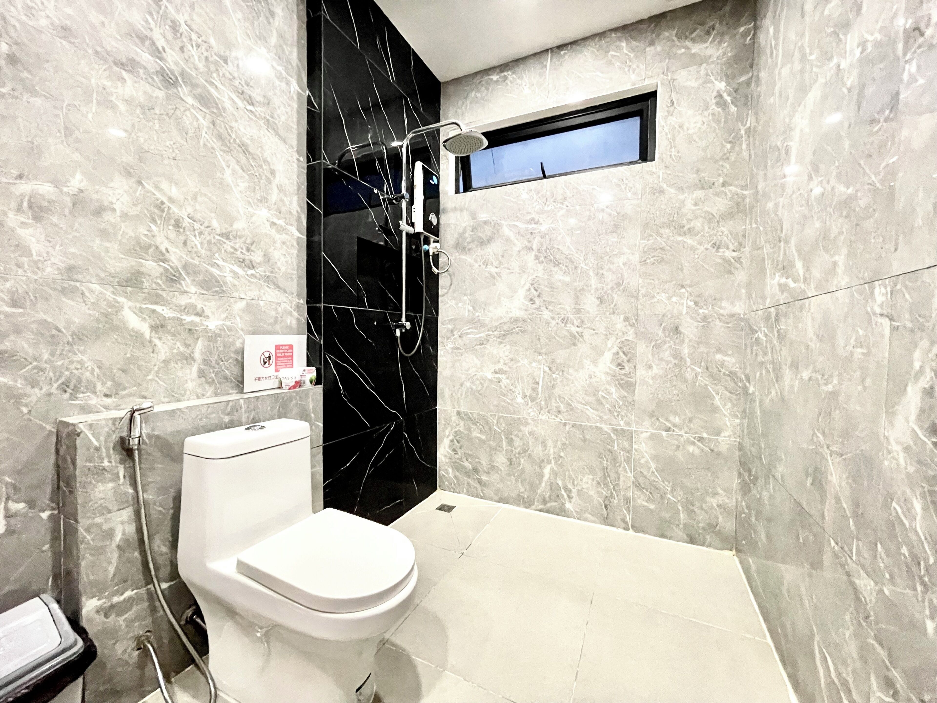 Un baño con inodoro, ducha y una ventana pequeña.