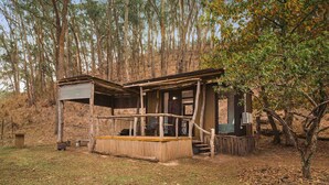 Eine rustikale Holzhütte mit einer Holzterrasse, einer Veranda und einer kleinen Sitzgelegenheit im Freien.
