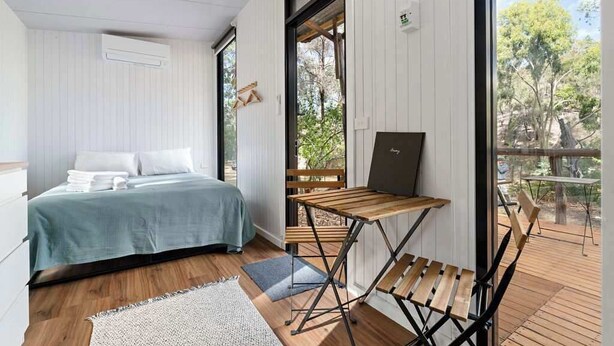 Ein Schlafzimmer mit einem Bett, einem Holztisch und Blick ins Freie.