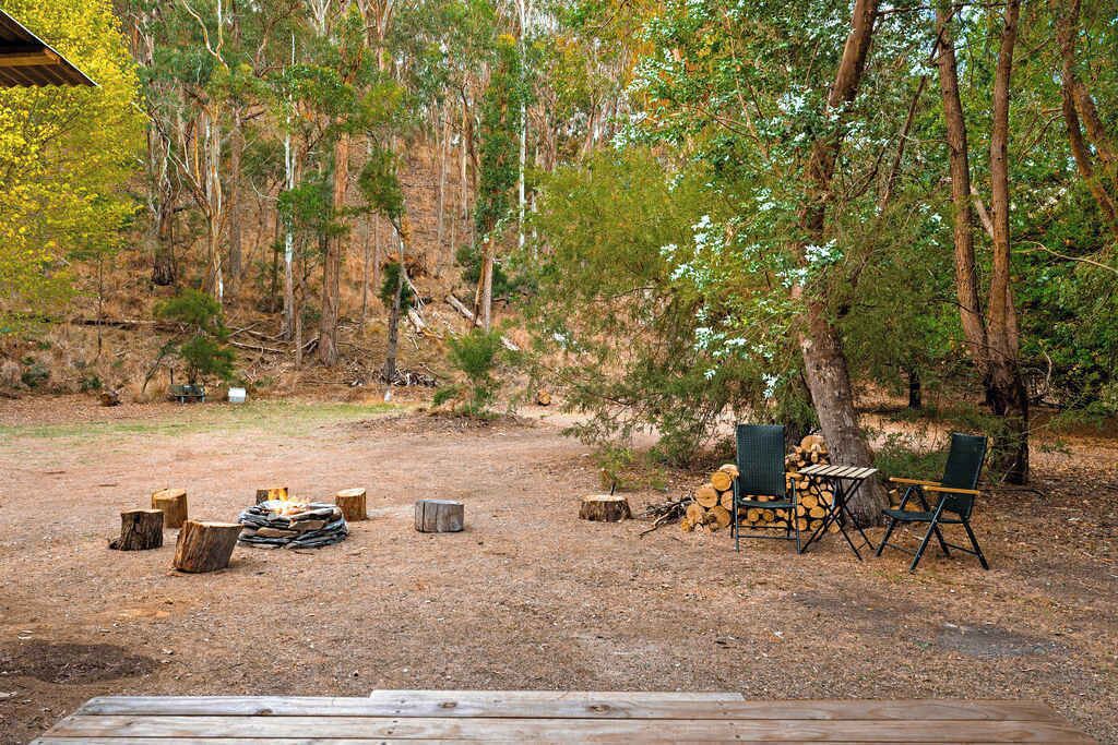 An outdoor camping area with a fire pit, chairs, and a table.