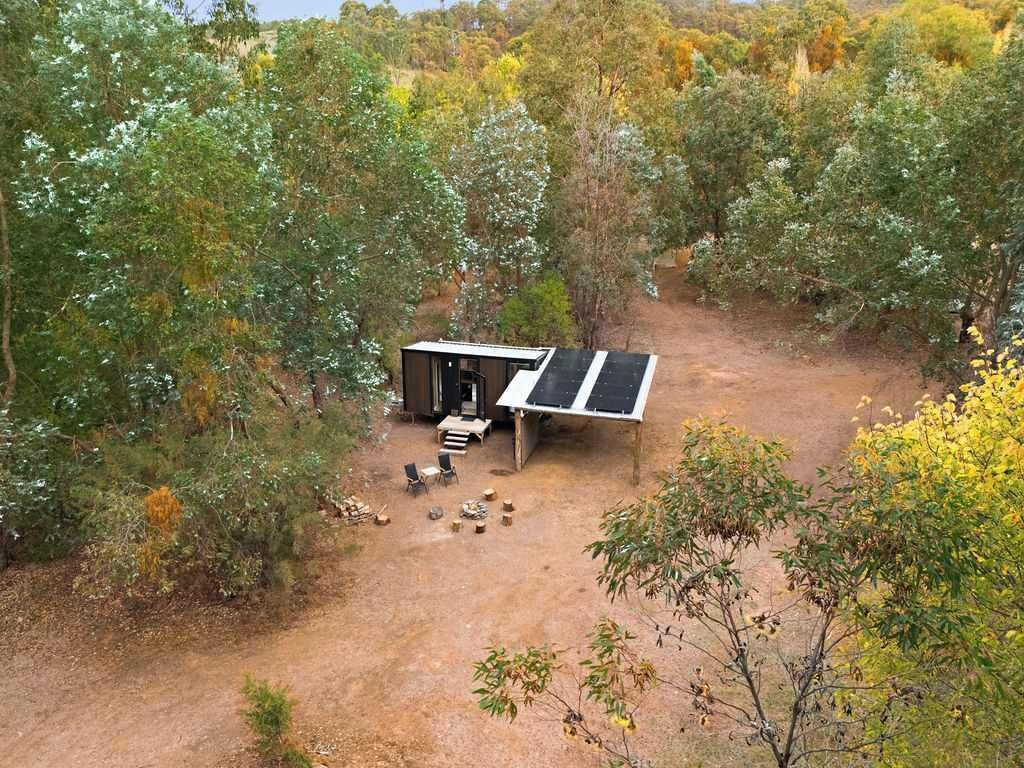 Un petit bâtiment d’un seul étage, doté d’un toit en pente, entouré d’arbres denses et bordé d’un sentier de terre.