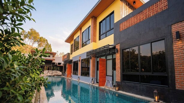 A modern hotel with a swimming pool, large windows, and a brick facade.