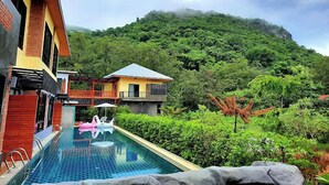 A swimming pool with a view of a mountain and a building with a balcony.