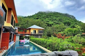 A swimming pool with a view of a mountain and a building with a balcony.