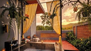 A hot tub area with a view of the landscape, surrounded by plants and a decorative wall.