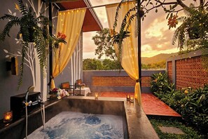 A hot tub area with a view of the landscape, surrounded by plants and a decorative wall.