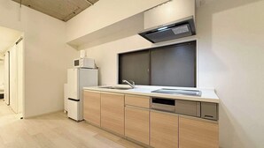 A modern kitchen with a built-in microwave, a sink, and a dishwasher. - Spacious 2BR Apt in Hatchobori for Up to 10 Guests (Hiroshima)