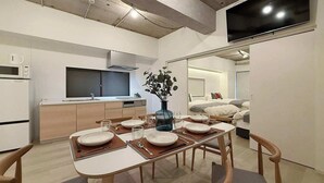 A modern kitchen with a microwave, oven, and a large flat-screen TV. - Spacious 2BR Apt in Hatchobori for Up to 10 Guests (Hiroshima)