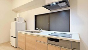 A modern kitchen with a built-in microwave, refrigerator, and dishwasher. - Comfortable 2BR Apt in Hatchobori - Sleeps 10 (Hiroshima)