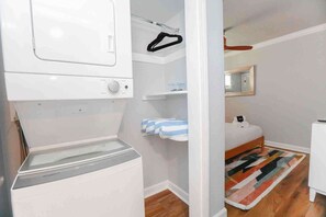 Une buanderie équipée d’un lave-linge et d’un sèche-linge à chargement frontal, d’un étendoir et d’une petite étagère sur laquelle est posée une serviette.