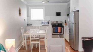 A compact kitchen with white cabinetry, a built-in oven, a microwave, and a stainless steel refrigerator.