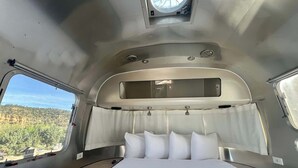 Een compact, goed verlicht interieur met een bed, een klein raam en een dakraam.
