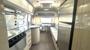 Een compact RV-interieur met een kitchenette, een eethoek en een kleine badkamer.