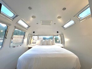 Ein Schlafzimmer mit Bett, Fenstern und einem Oberlicht.