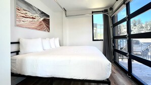 Ein Schlafzimmer mit einem Bett, einem großen Fenster und einem Gemälde an der Wand.