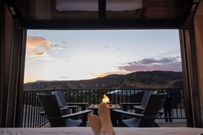 A balcony with chairs and a table, overlooking a mountainous landscape.