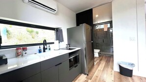Eine moderne Küche mit Backofen, Edelstahlkühlschrank und einem Fenster mit Blick ins Freie.