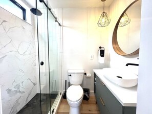 A modern bathroom with a glass shower enclosure, a toilet, a sink with a mirror, and pendant lighting. - Valley View Summary: (Orderville)