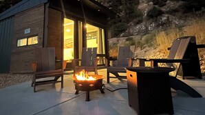 A wooden cabin with a fire pit, outdoor seating, and a view of a hillside. - Modern Cabin Near Zion & Bryce National Parks (Orderville)
