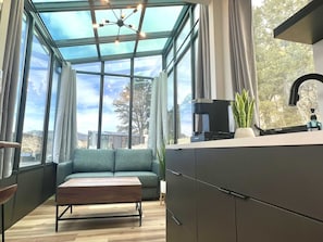 Una cocina moderna con techo de cristal, un sofá y una cafetera.