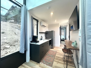 A modern kitchen with a coffee machine, a refrigerator, and a dining area with a bar stool. - Stargazing cabin near Bryce & Zion w/resort pools (Orderville)
