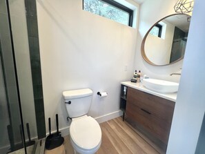 Ein modernes Badezimmer mit Toilette, Waschbecken und Spiegel.