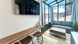 En moderne stue med et stort vindue, en sofa, et sofabord og et barområde med barstole.