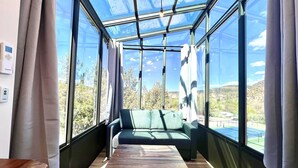Een kamer met een glazen plafond, een groene bank en een houten tafel.
