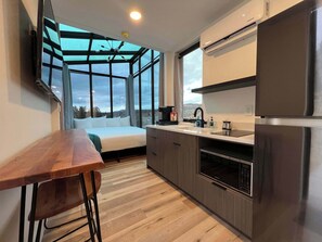 A modern kitchen with a large window, a built-in oven, and a refrigerator.