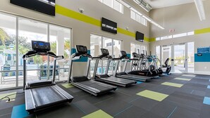 Ein Fitnessstudio mit Laufbändern, Hantelbänken und einem großen Fenster für natürliches Licht.