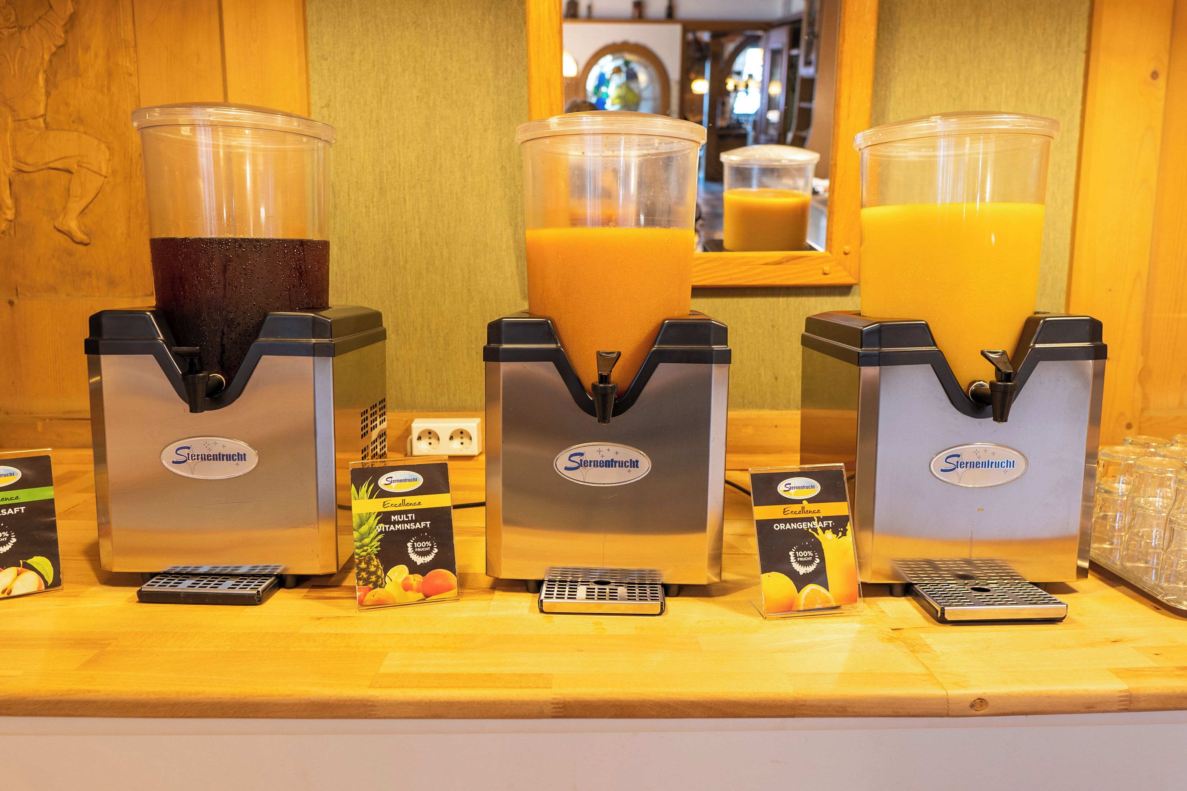 Un bar de zumos con tres dispensadores, cada uno con un tipo diferente de jugo.