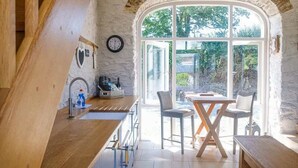 A kitchen with a wooden counter, a sink, and a dining area with a table and chairs.